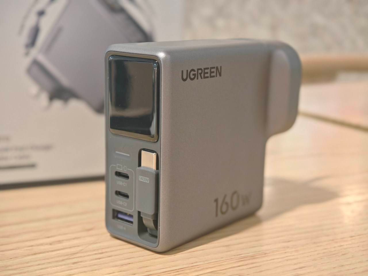 Front and side view of the UGREEN Nexode Pro 160W charger showing its display, USB ports and built-in cable