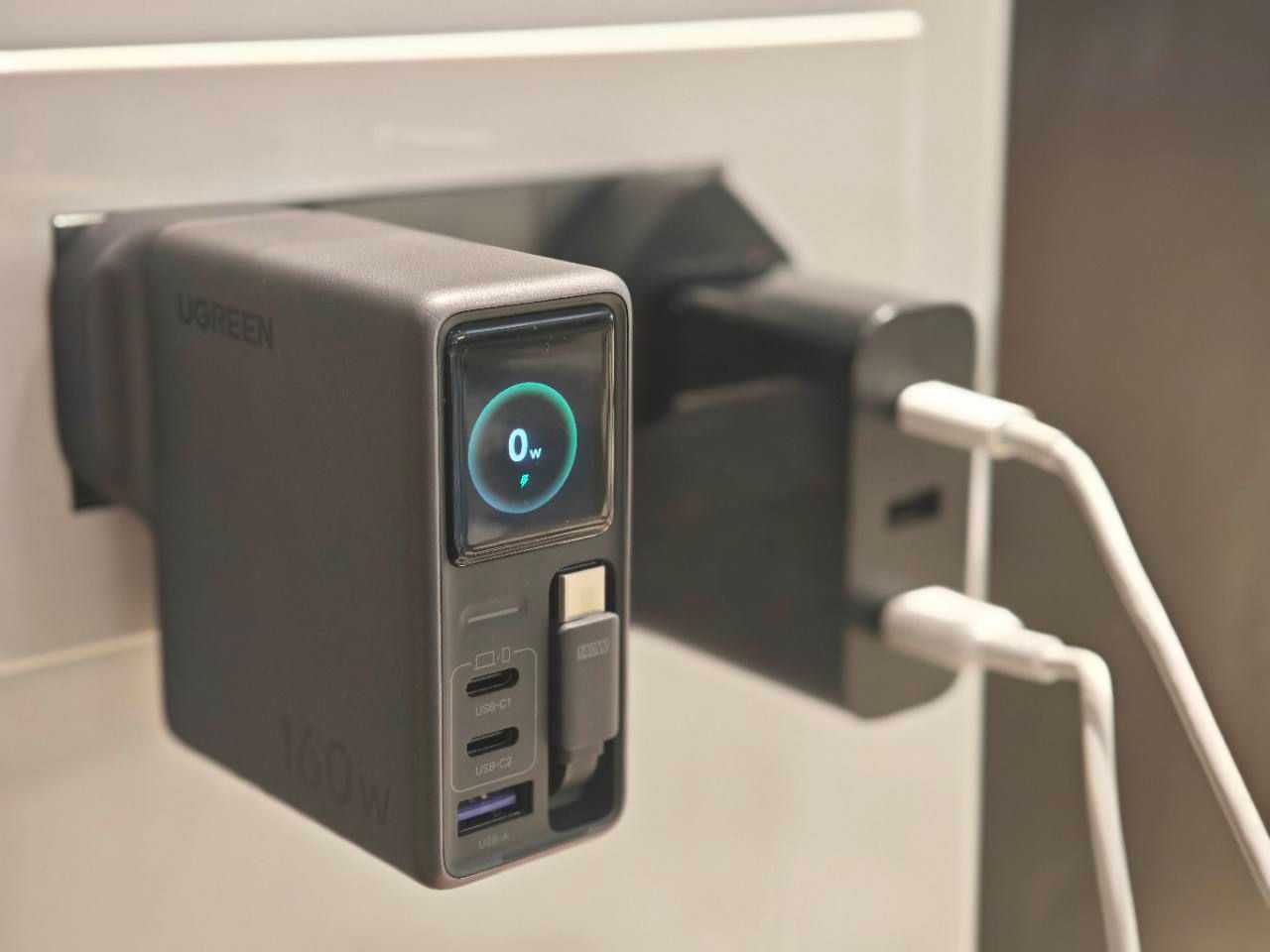 UGREEN Nexode Pro 160W charger plugged into a wall socket with its idle display lit